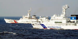 沖縄県・尖閣諸島海域で、中国公船（奥）を監視する海上保安庁の巡視船（海上保安庁提供）
