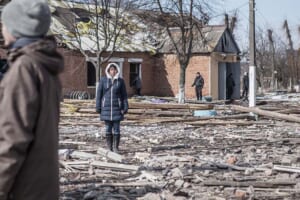 １７日、ロシアのミサイルで破壊されたウクライナ北東部ハリコフ州の学校敷地で立ち尽くす人々（ＡＡ時事）