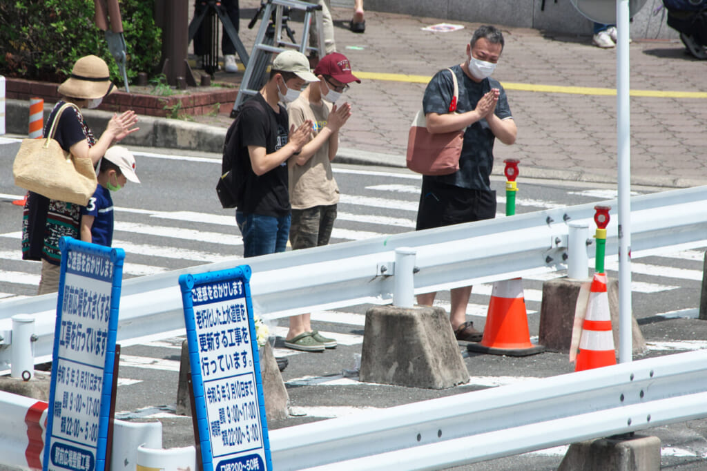 安倍晋三元首相が銃撃された事件から1カ月となり、現場付近で手を合わせる人たち =2022年8月8日午後、奈良市